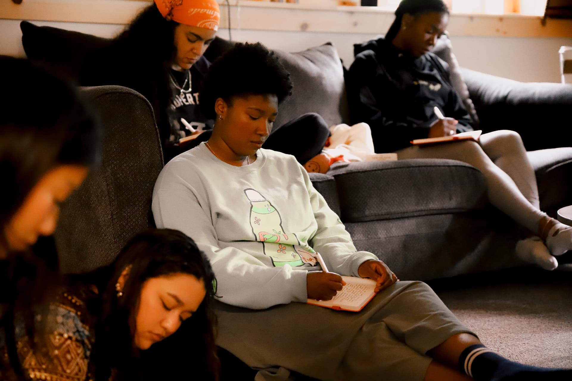 Retreat guests journaling together in a warm, candlelit living room