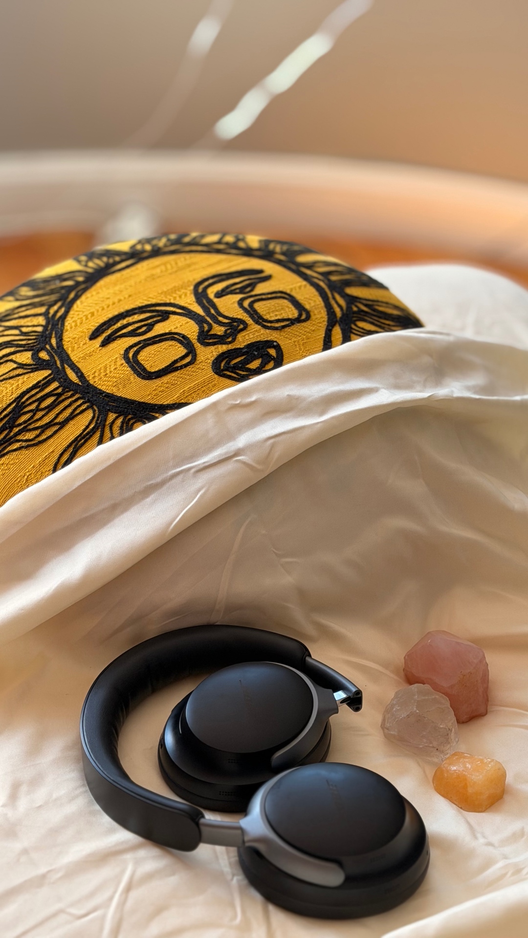 Noise cancelling headphones and crystals laid out beside the sun cushion