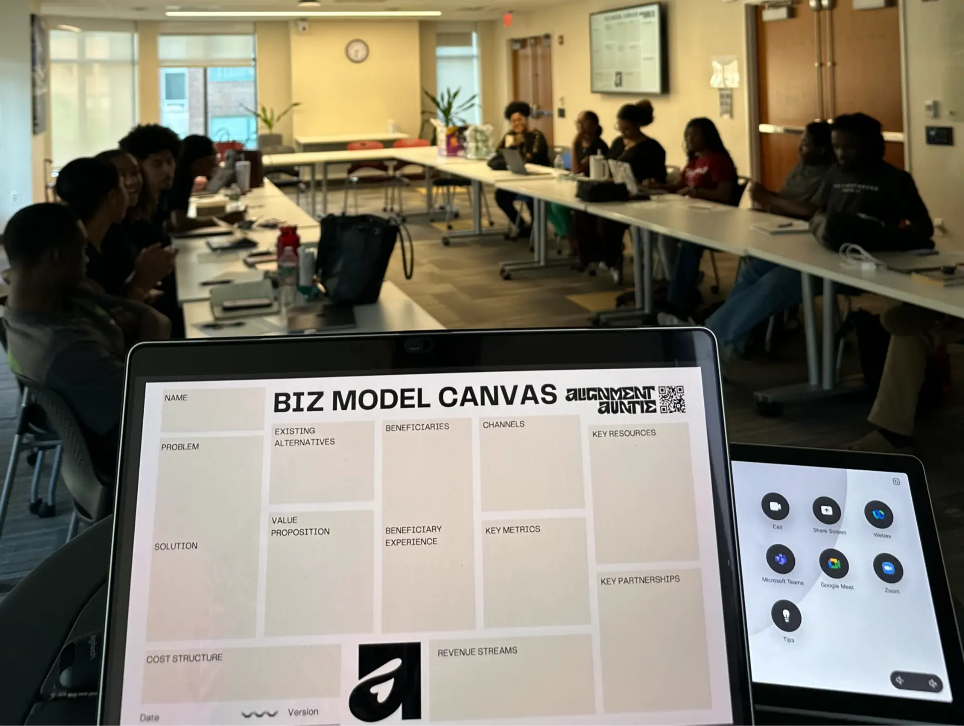 A business model canvas on screen during a workshop for a seated group