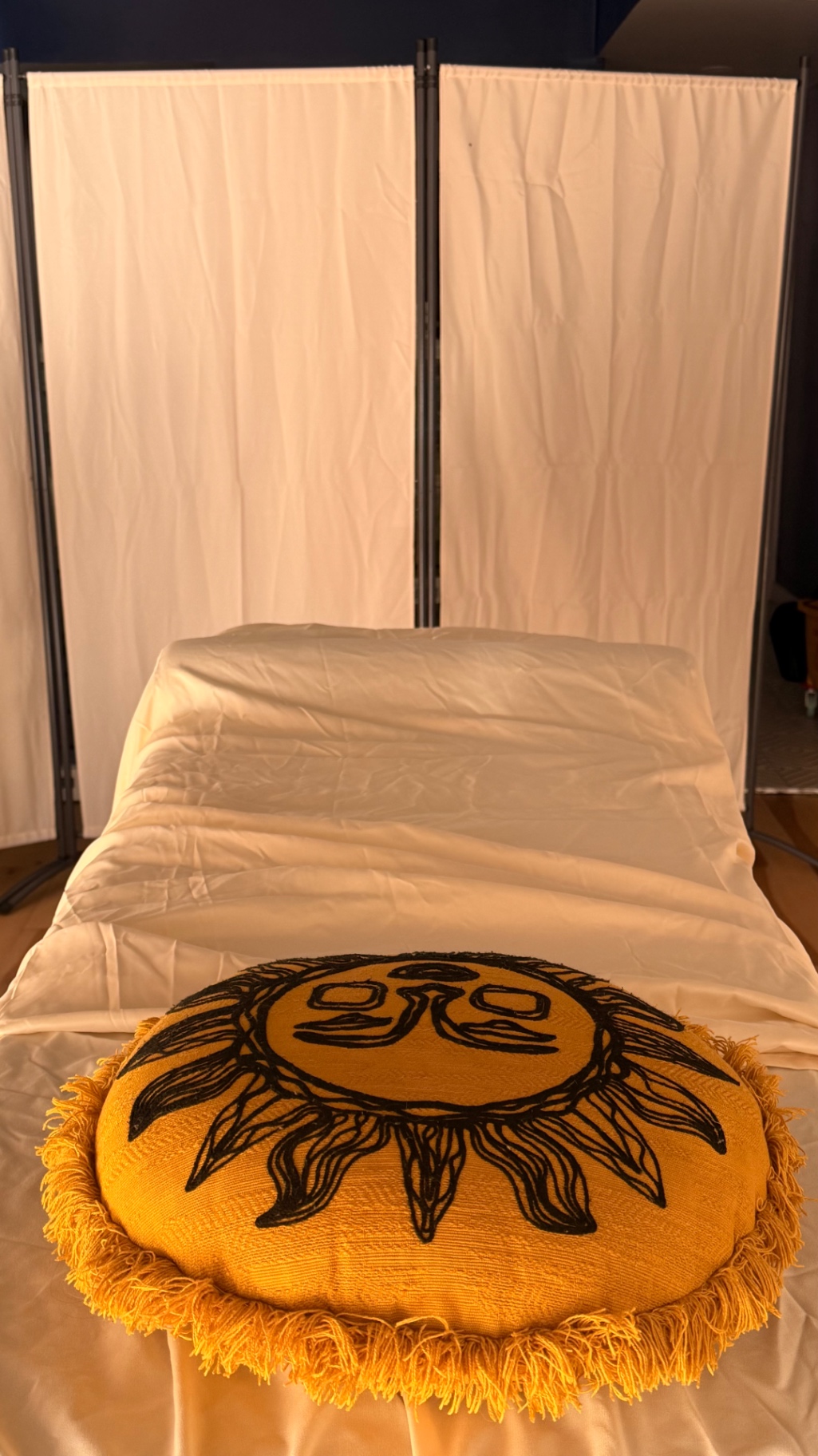 Reiki table set with linen and the sun cushion behind a privacy screen