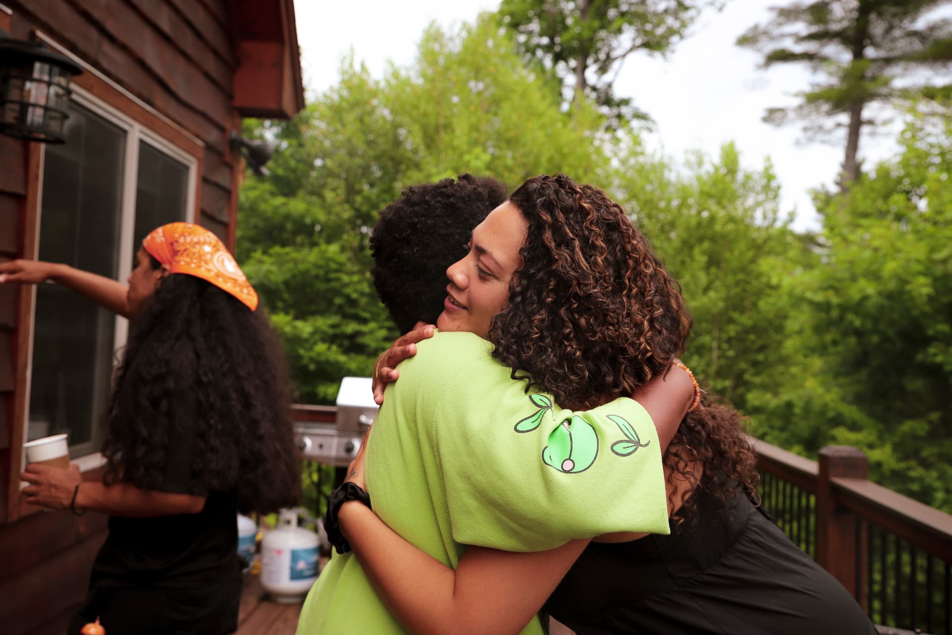 Two retreat guests holding each other in a long embrace on a wooded deck