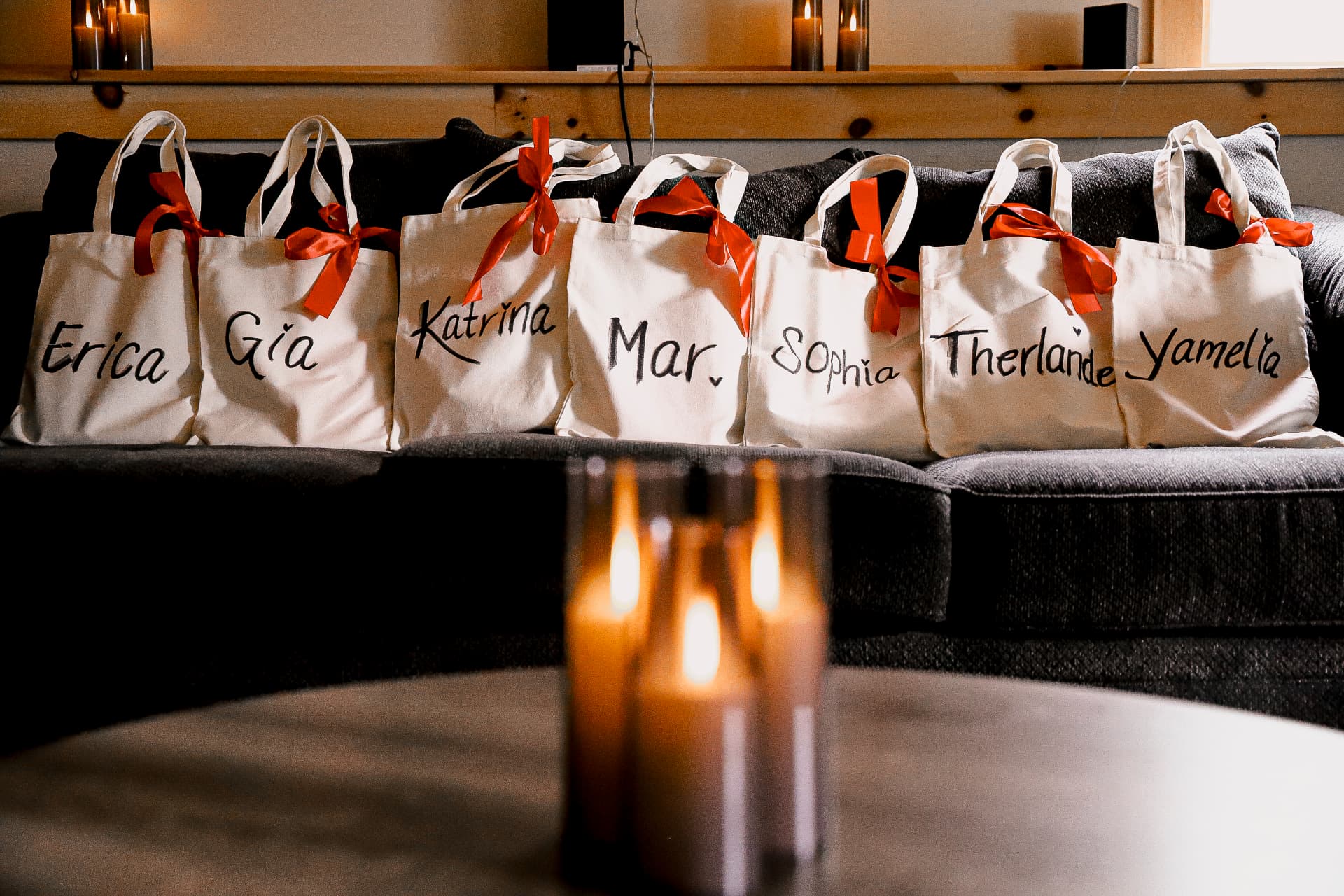 Hand lettered welcome totes with red ribbons lined up for retreat guests